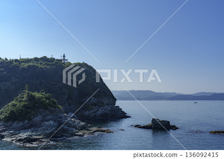 A Japanese coastal landscape with a lighthouse on a cape and a calm sea 136092415