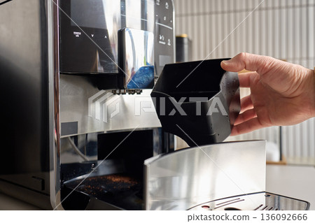 Man removing coffee grounds container from automatic coffee machine Man removing coffee grounds container from automatic coffee machine 136092666