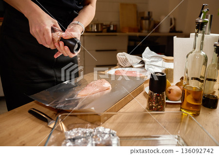 Seasoning raw chicken breast with salt on kitchen counter Seasoning raw chicken breast with salt on kitchen counter 136092742