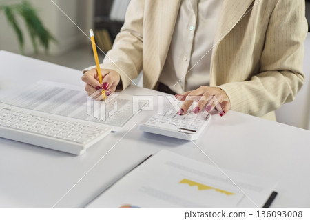 Female accountant auditing finance data with calculator in modern office 136093008