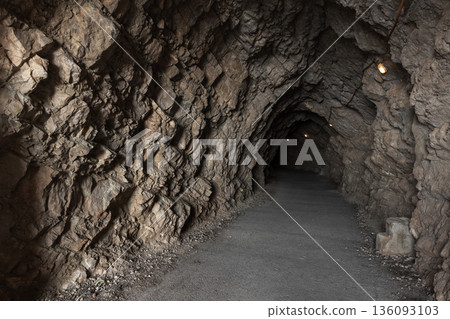 A narrow path winds through a rocky cave tunnel A narrow path winds through a rocky cave tunnel 136093103