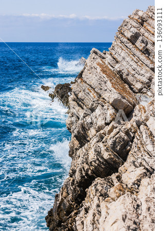 Rugged rocky cliffs meet the deep blue sea Rugged rocky cliffs meet the deep blue sea 136093111