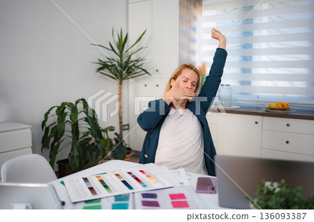 Tired woman yawning and stretching working from home 136093387