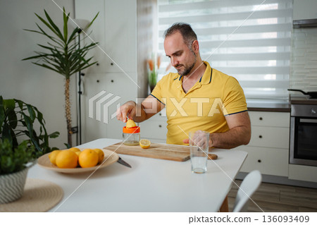 Man squeezing fresh lemon juice for healthy lifestyle drink 136093409