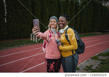 Diverse athletic women friends taking selfie on running track 136093424