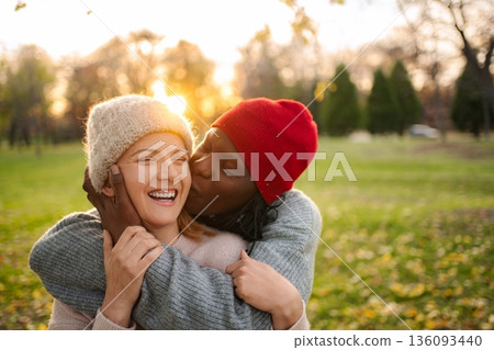 Interracial couple sharing happy kiss in sunny autumn park 136093440