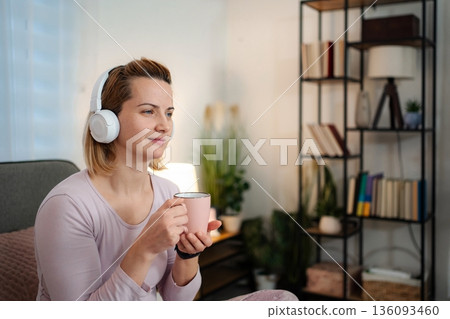 Woman relaxing at home listening to music 136093460