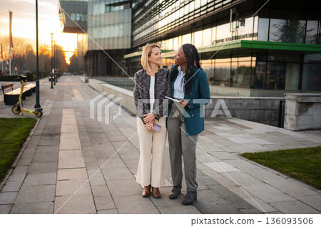 Diverse businesswomen walking discussing work after meeting Diverse businesswomen walking discussing work after meeting 136093506