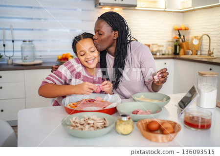 Mother and daughter making pizza bonding in kitchen 136093515