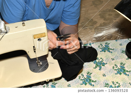 The seamstress works on a sewing machine. The seamstress works on a sewing machine. 136093528