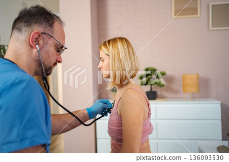 Doctor using stethoscope checking woman with rash at home Doctor using stethoscope checking woman with rash at home 136093530