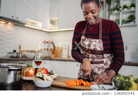 African woman chopping vegetables for healthy dinner in kitchen African woman chopping vegetables for healthy dinner in kitchen 136093545