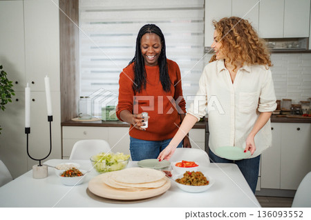 Diverse women cooking and preparing dinner for friendship in kitchen Diverse women cooking and preparing dinner for friendship in kitchen 136093552