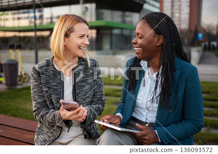 Diverse businesswomen laughing enjoying break with mobile technology 136093572