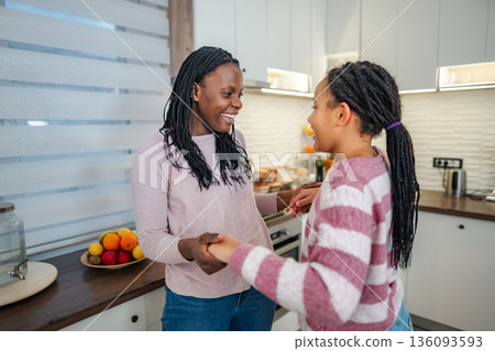 Mother and daughter dancing in kitchen at home Mother and daughter dancing in kitchen at home 136093593