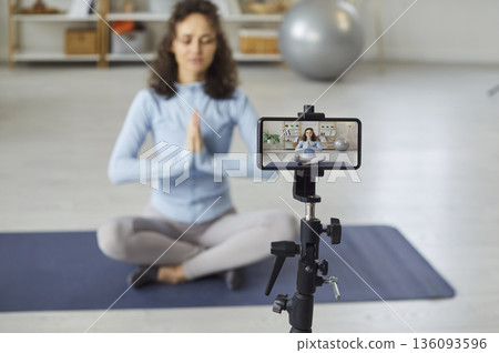 Woman recording yoga practice and meditation video on her smartphone at home Woman recording yoga practice and meditation video on her smartphone at home 136093596
