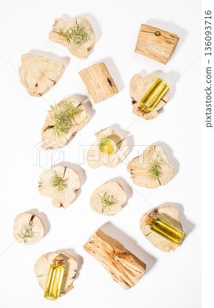 Flat lay arrangement of essential juniper oil bottles on wooden juniper slices with leaves on white. 136093716