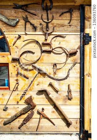 Assorted old rusty metal work tools on wooden wall. Vintage household tools hang on the wall 136093760