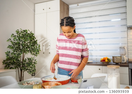 Young girl learning cooking baking homemade pizza using tablet 136093939