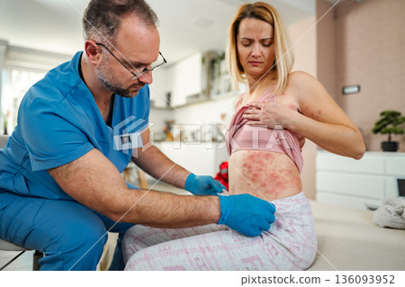 Doctor examining a woman experiencing skin rash at her home Doctor examining a woman experiencing skin rash at her home 136093952