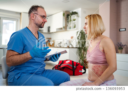 Doctor examining a female patient with skin rash at her home Doctor examining a female patient with skin rash at her home 136093953