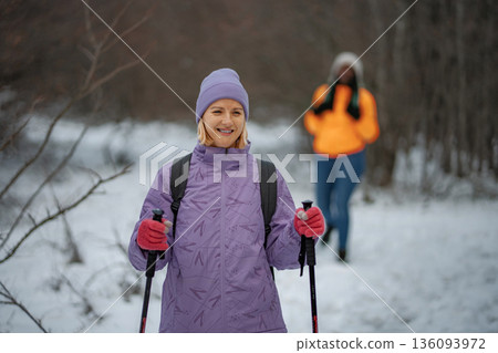 Woman nordic walking in winter forest enjoying nature 136093972