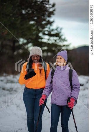 Two women winter hiking using smartphone for navigation Two women winter hiking using smartphone for navigation 136093973