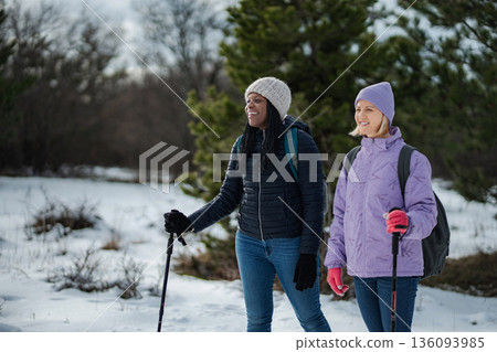 Two women hiking in winter forest enjoying outdoor exercise 136093985