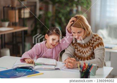 Young girl assisting her stressed mother with homework at home Young girl assisting her stressed mother with homework at home 136094002