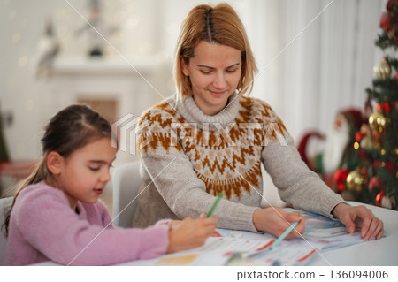 Mother daughter coloring Christmas holiday together at home Mother daughter coloring Christmas holiday together at home 136094006