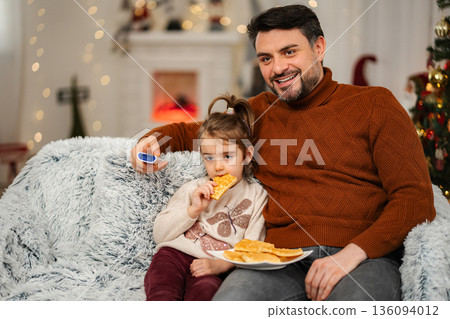 Father and daughter enjoying cozy holiday evening at home Father and daughter enjoying cozy holiday evening at home 136094012