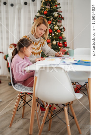 Mother helping daughter with homework during Christmas holidays Mother helping daughter with homework during Christmas holidays 136094024