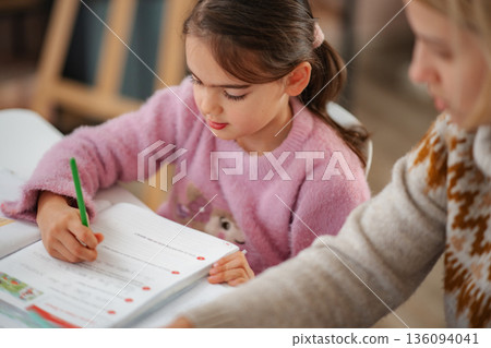 Little girl learning writing skills with an adult tutor Little girl learning writing skills with an adult tutor 136094041