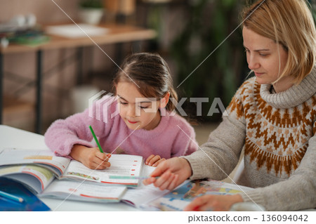 Mother and daughter studying together at home Mother and daughter studying together at home 136094042