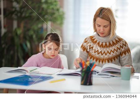 Mother and daughter studying together doing homework Mother and daughter studying together doing homework 136094044