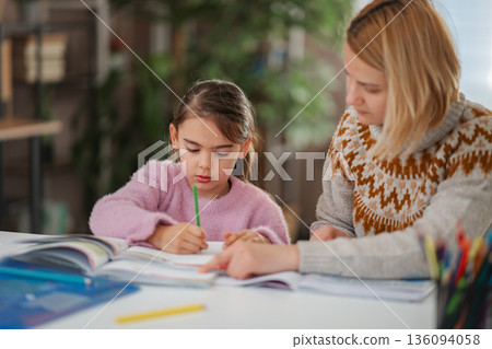 Teacher helping young student with her homework Teacher helping young student with her homework 136094058