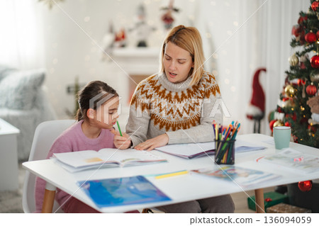 Mother helping daughter with Christmas holiday homework at home Mother helping daughter with Christmas holiday homework at home 136094059