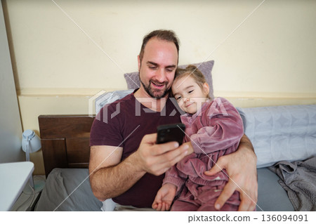Father and daughter bonding while using smartphone in bed 136094091