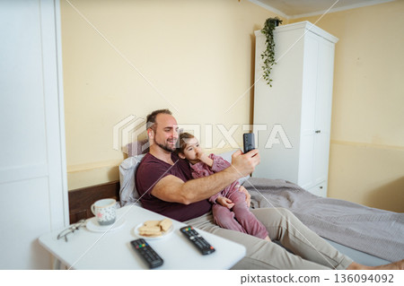 Father daughter bonding taking a selfie in bed 136094092