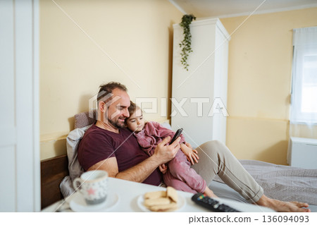 Father and daughter using smartphone in bed Father and daughter using smartphone in bed 136094093