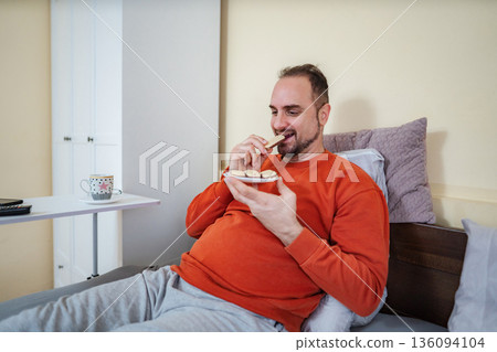 Adult man enjoying sweet cookies in bed at home Adult man enjoying sweet cookies in bed at home 136094104