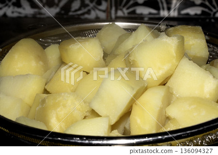 Close up of chopped and boiled potatoes in cubes waiting to be roasted or mashed food prep Close up of chopped and boiled potatoes in cubes waiting to be roasted or mashed food prep 136094327