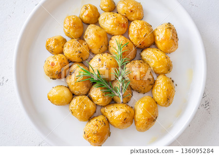 Oven baked baby potatoes seasoned with herbs served in white ceramic bowl 136095284