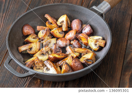 Sauteed brown champignon mushrooms in rustic cast iron skillet Sauteed brown champignon mushrooms in rustic cast iron skillet 136095301