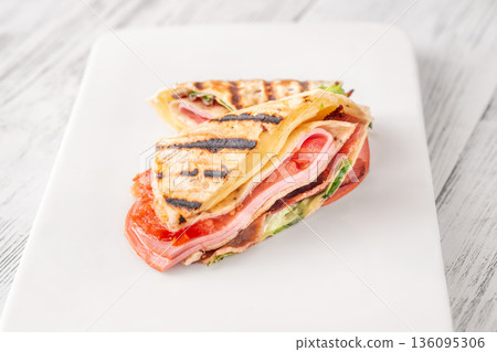 Folded tortilla wrap with cheese bacon ham and tomatoes on clean background 136095306