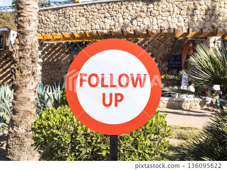 Follow up symbol. Concept word Follow up on beautiful red and white road sign. Beautiful palm tree and market background. Business follow up concept. Copy space. Follow up symbol. Concept word Follow up on beautiful red and white road sign. Beautiful palm tree and market background. Business follow up concept. Copy space. 136095622