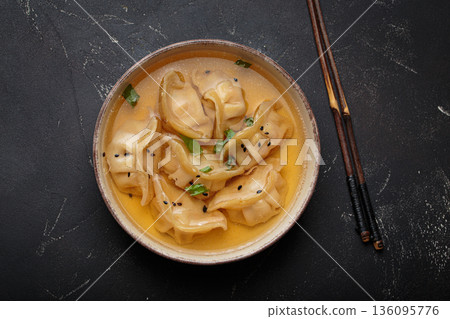 Gyoza dumplings broth soup chopsticks dark background bowl asian wontons Gyoza dumplings broth soup chopsticks dark background bowl asian wontons 136095776