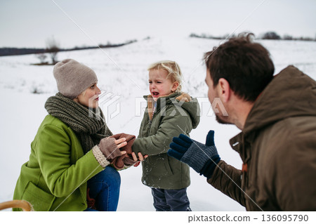 Parents and little son on walk in winter forest, during snowfall. 136095790