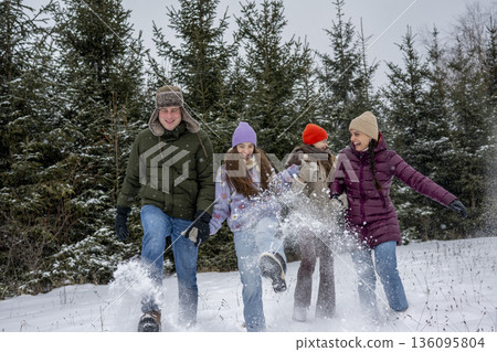 Parents and daughters playing in snow during joyful winter day. Parents and daughters playing in snow during joyful winter day. 136095804