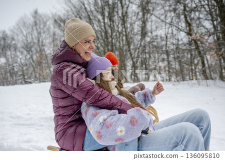 Family enjoying winter sledding together on snowy hill. Family enjoying winter sledding together on snowy hill. 136095810